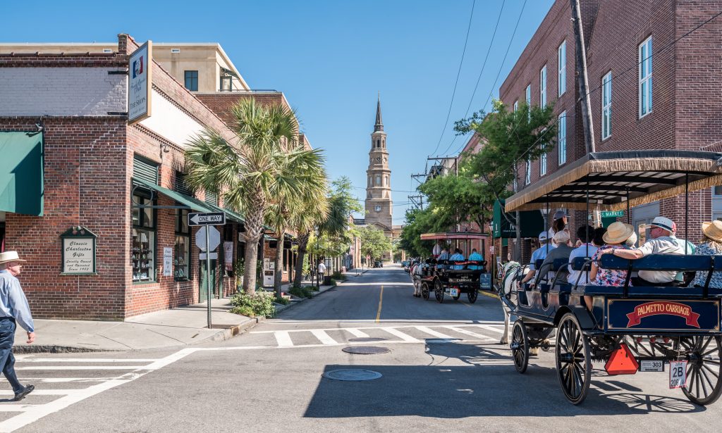 Two horse-drawn carriages with passengers on the streets of Charleston, South Carolina.
