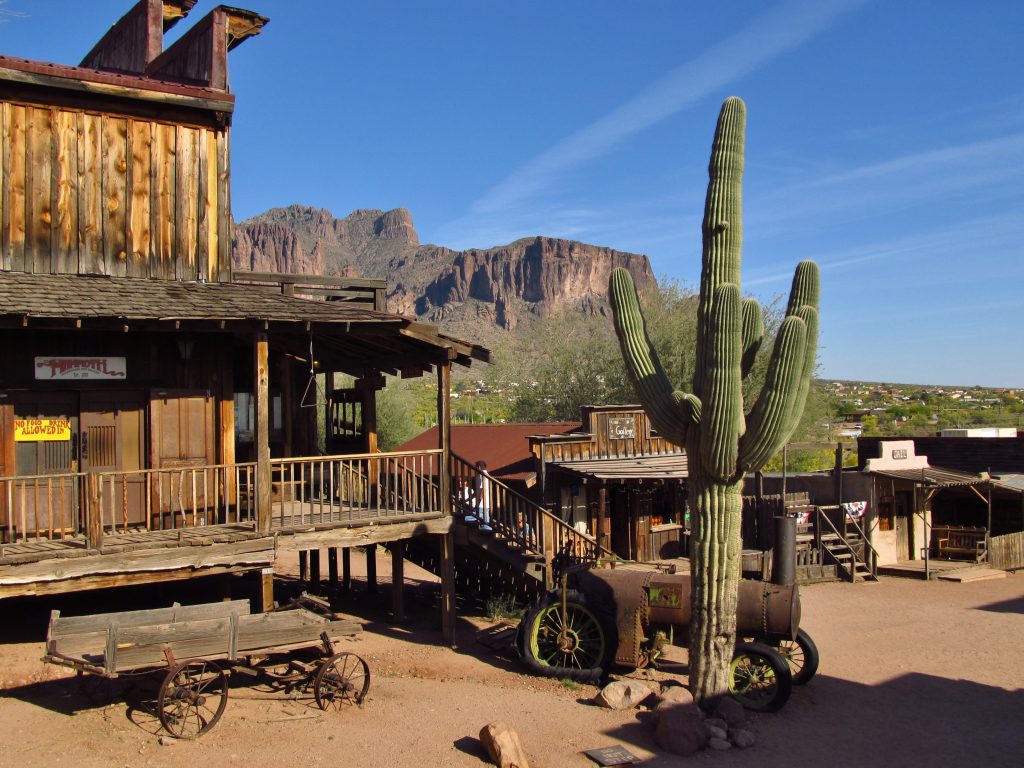 Old buildings, old-time vehicles, and a gigantic cactus erected beside the structure in the streets of Goldfield, a ghost town near Phoenix. 