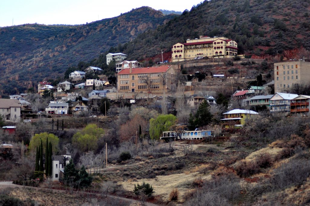 Wide shot of abandoned buildings and houses in Jerome, one of the ghost towns in Arizona, with mountains in the background.