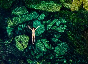 A woman in a bikini floating in Cenote Cristalino, one of the cenotes near Tulum.