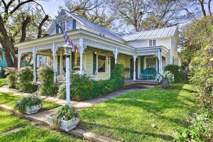 Exterior of a rental house with the US flag, one of the places to stay in Fredericksburg, TX.