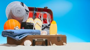 Open suitcase filled with an assortment of different beach essentials and items.