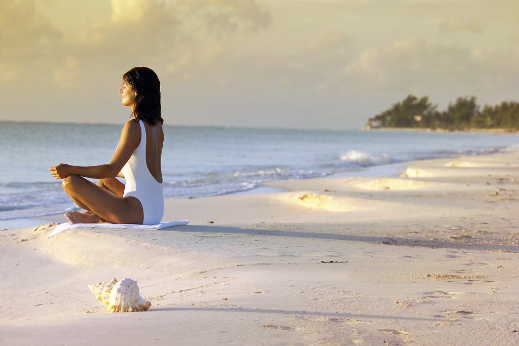 A woman meditating by the beach.