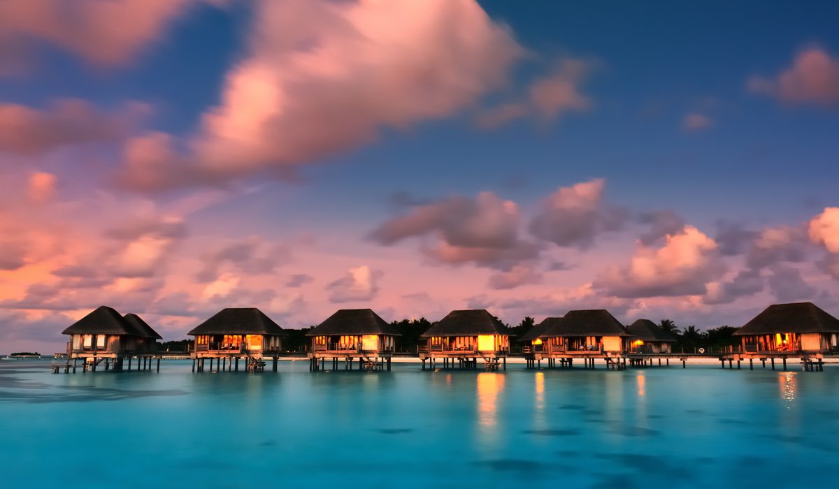 Water bungalows in Maldives against a twilight sky.