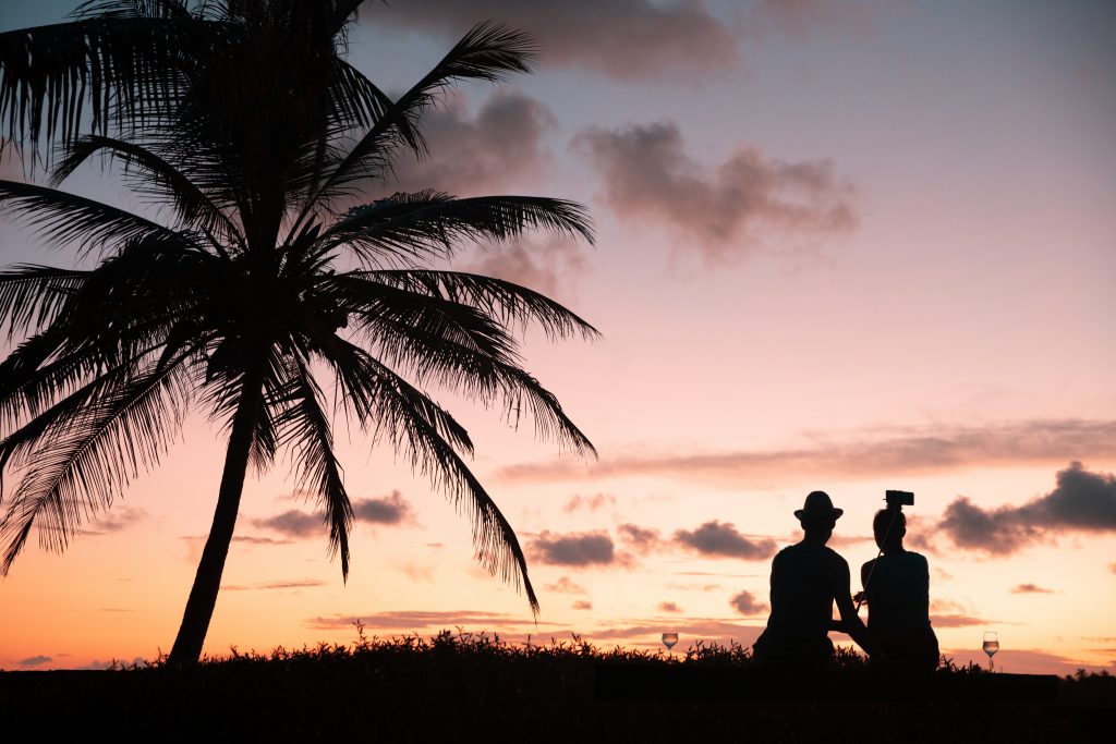 Silhouette of a couple near a palm tree during sunset in Maldives.