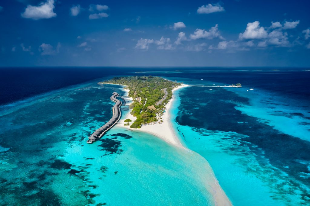 Aerial shot of one of the atolls and resorts in Maldives; surrounded by a body of water.