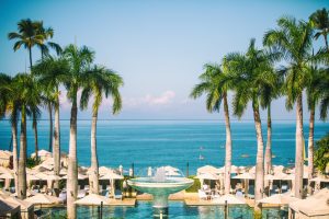 Wide shot of the ocean, palm trees, and beach tents seen from one of the resorts in Maui, Hawaii.