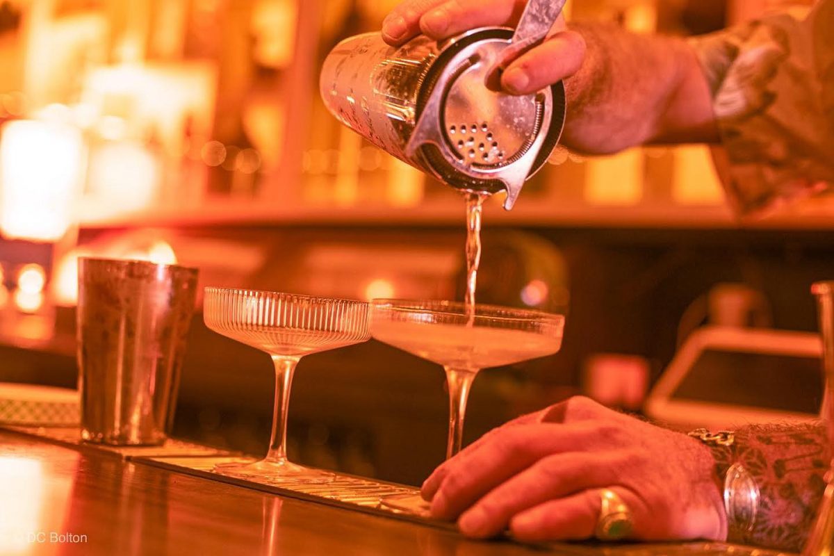 Close-up shot of cocktail being poured into martini glasses. 