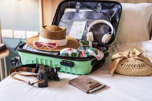 Open luggage displaying items to include in a Hawaii packing list laid out on a bed.