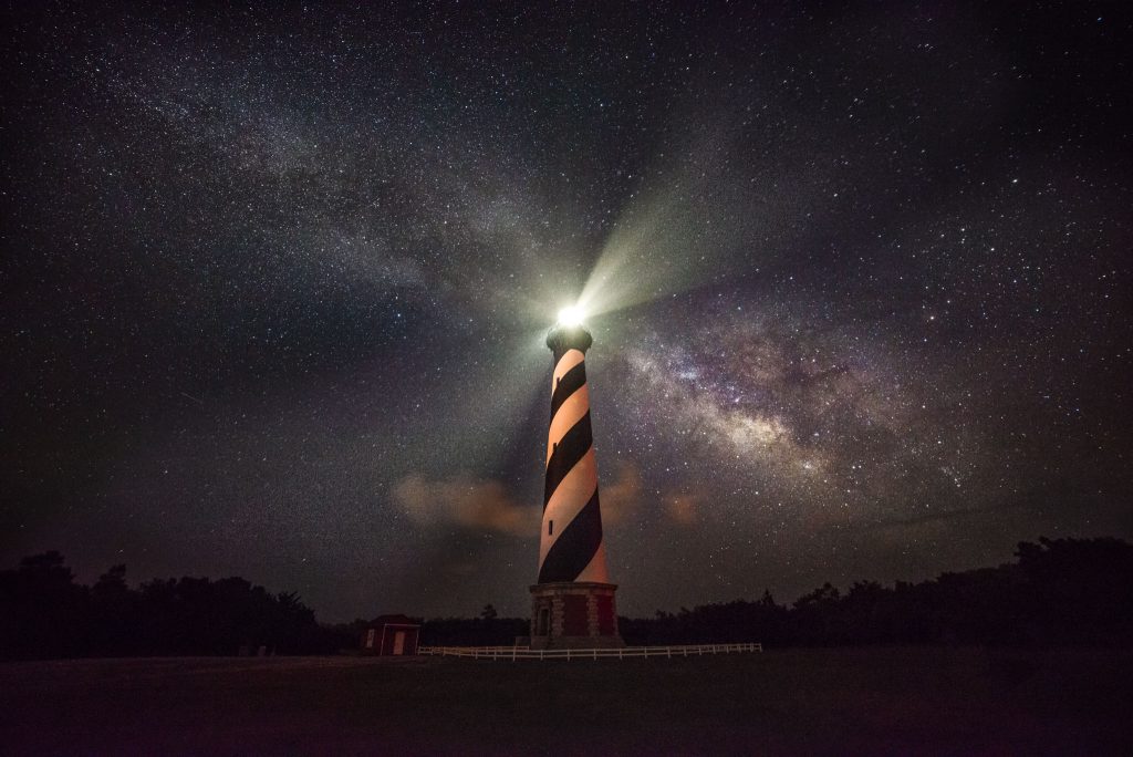 One of the historic lighthouses at Outer Banks, North Carolina against a starry night sky. 