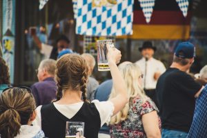 Woman raising an almost empty beer stein in the middle of the crowd of Oktoberfest.