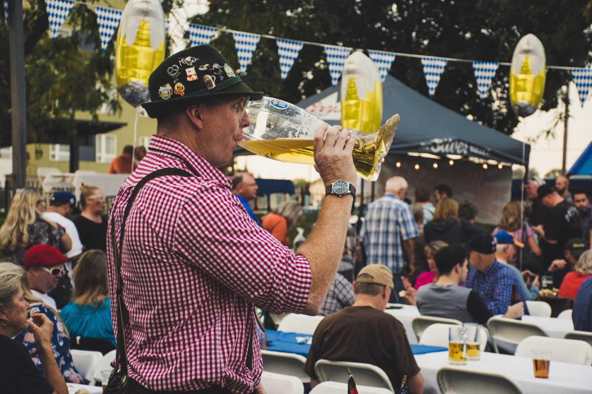 Man dressed in traditional German clothing drinking beer during an Oktoberfest near me.