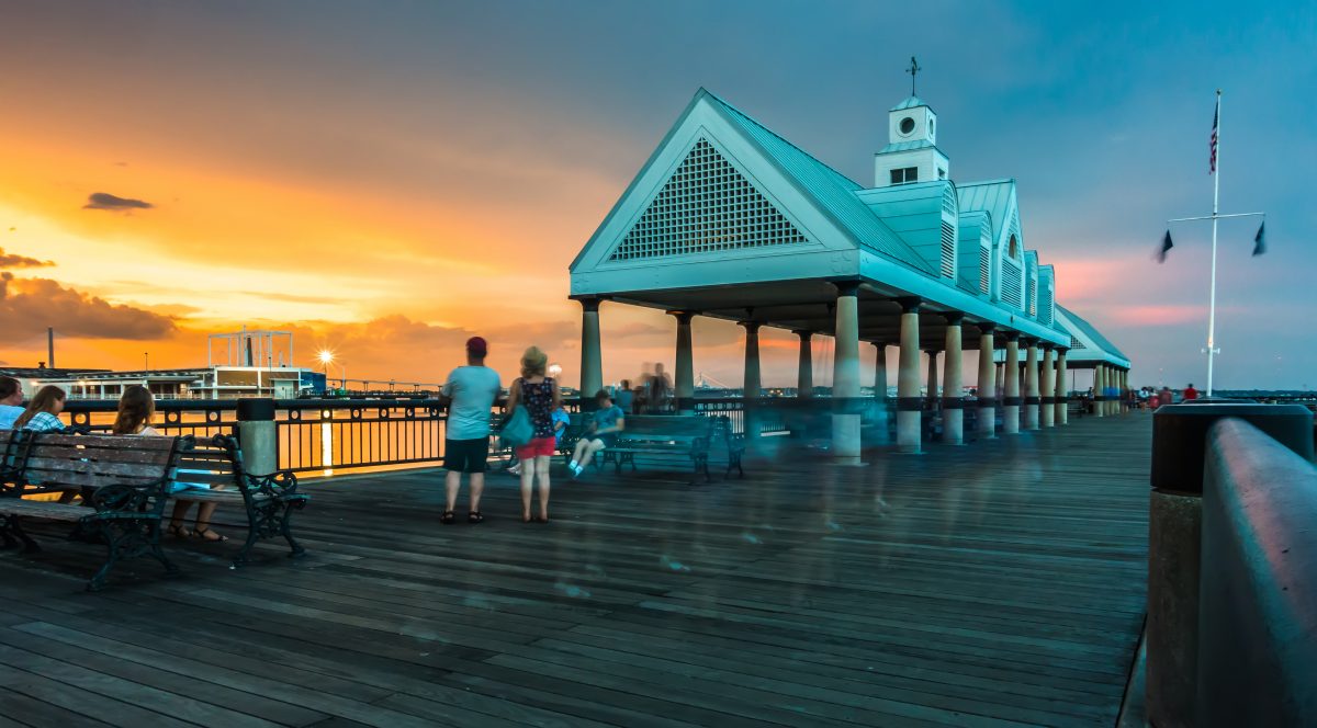 People along the harbor and pier area of Charleston, South Carolina during sunset.