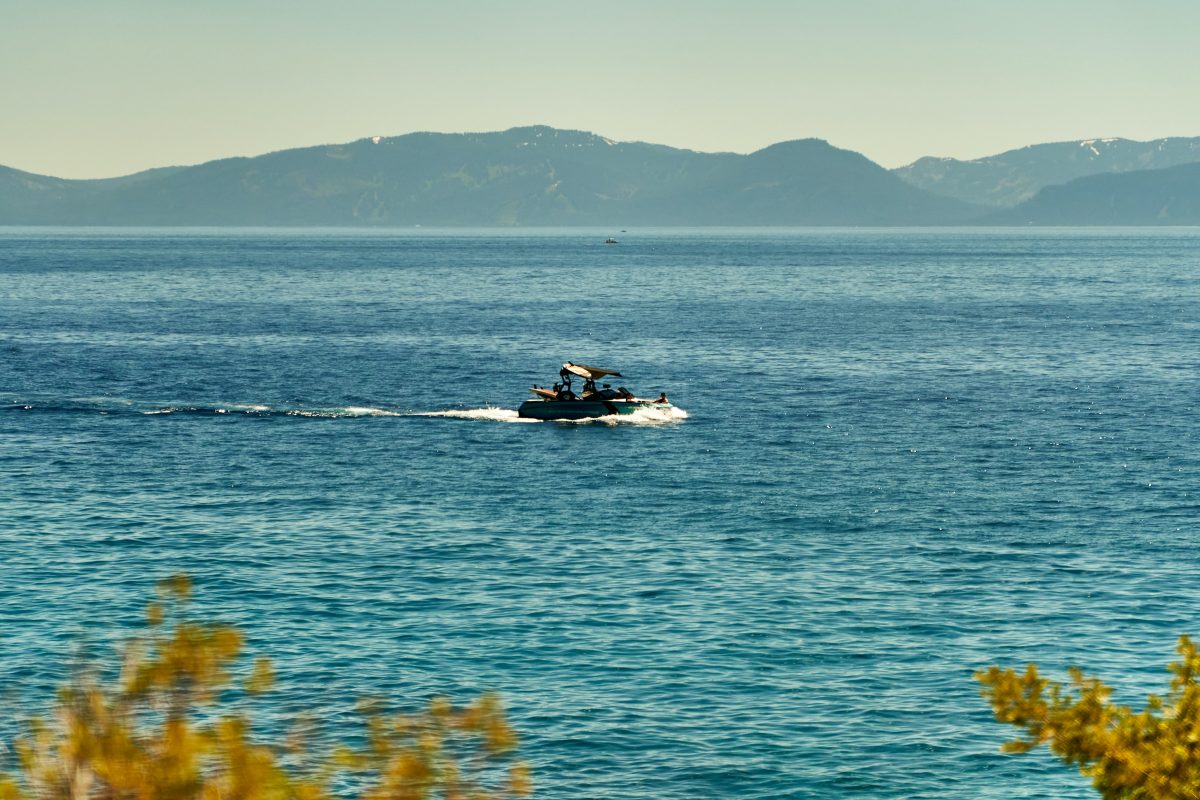 Wide shot of Lake Tahoe during fall with a motorboat in the water.