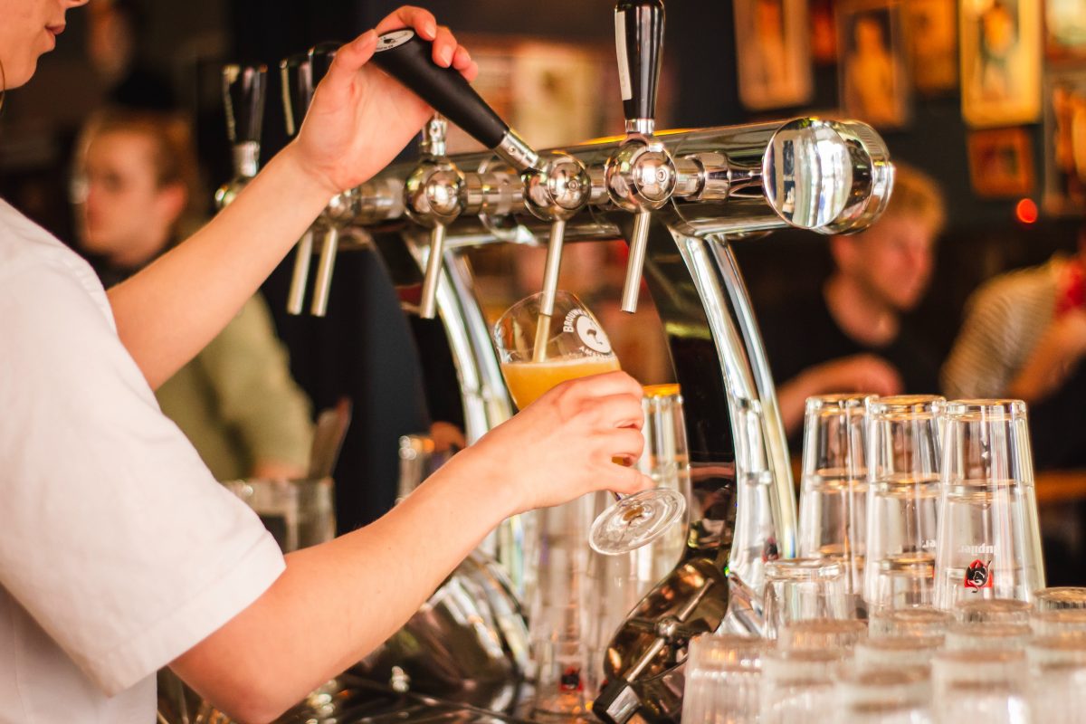 Person filling mug with beer from a beer tap.