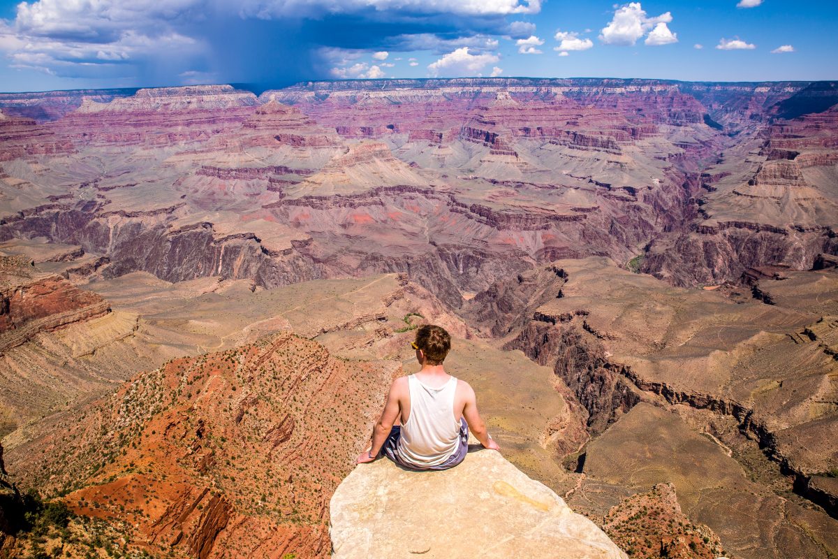 Man sitting on the edge of a cliff during daytime at Grand Canyon National Park.