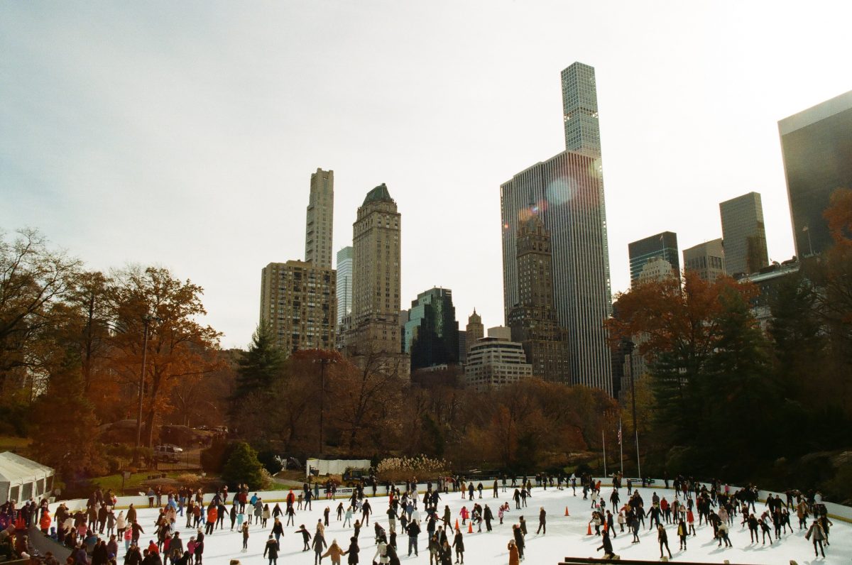 Wide shot of people gliding across on an outdoor ice skating rink, one of the 15 fun things to do in the fall.
