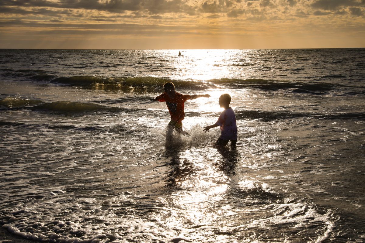 Silhouette of little kids playing in the waters of Indian Rocks Beach, Florida.