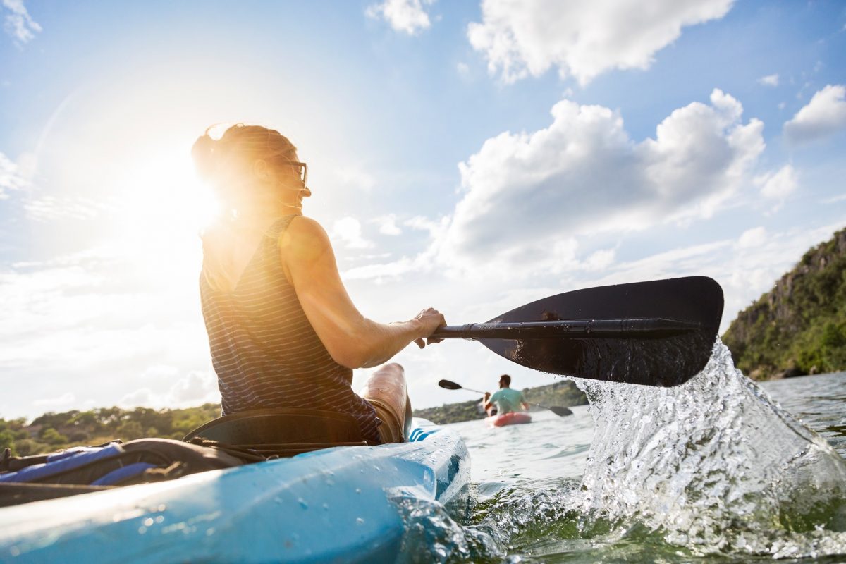 Perspective shot of a woman kayaking in the waters of Marble Falls, Texas, one of the 15 fun things to do in the fall.