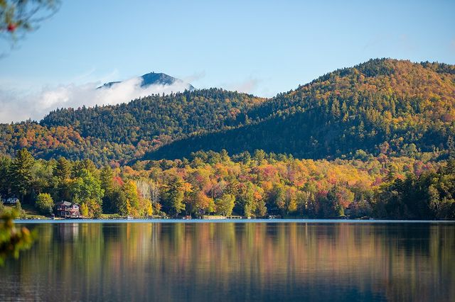 Wide shot of Lake Placid with hills covered in fall foliage in the background.