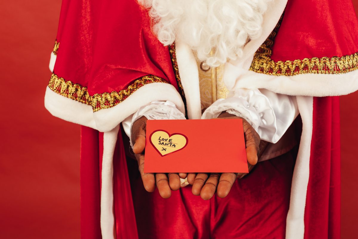 Hand holding a red envelope with “love Santa” written on it, one of the best souvenirs from Alaska for kids.