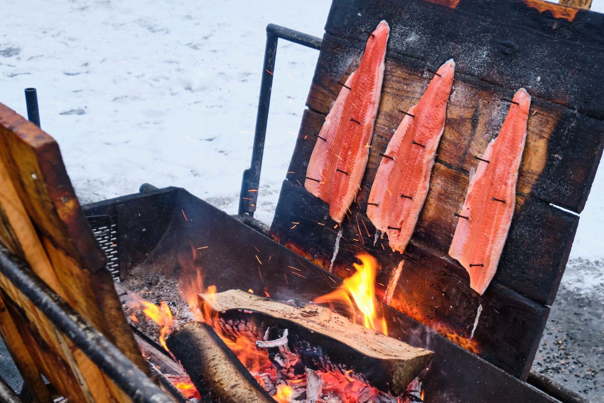 Fresh-caught salmon over a traditional smoker, one of the best souvenirs from Alaska for foodies.