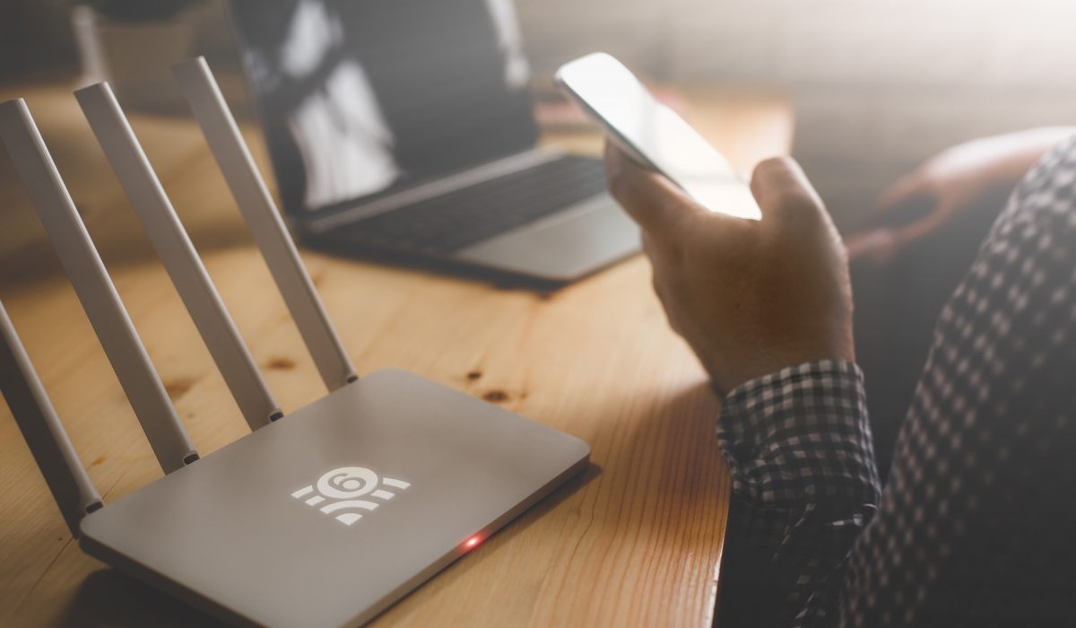 Wireless travel router with a person using a smartphone and laptop.