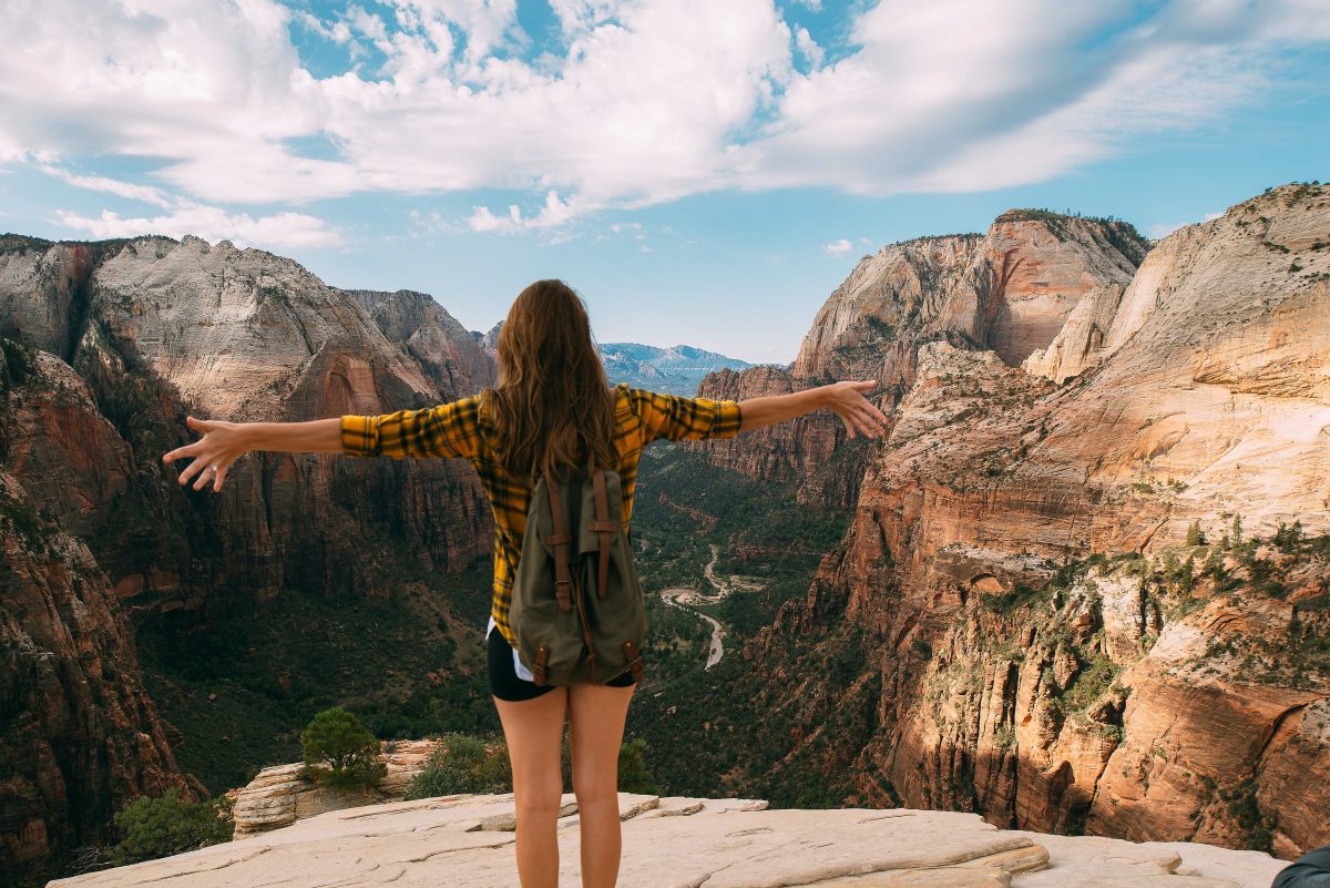 Woman on top of Angels Landing Overlook at Zion National Park, one of the best places to visit at the end of September in the USA.