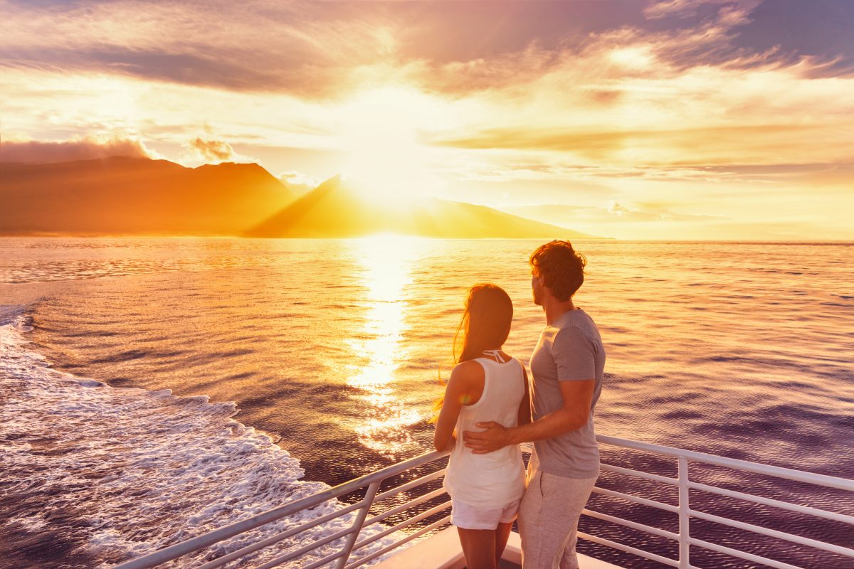 couple on a sunset cruise in the waters of hawaii, one of the best places to visit in october in usa.