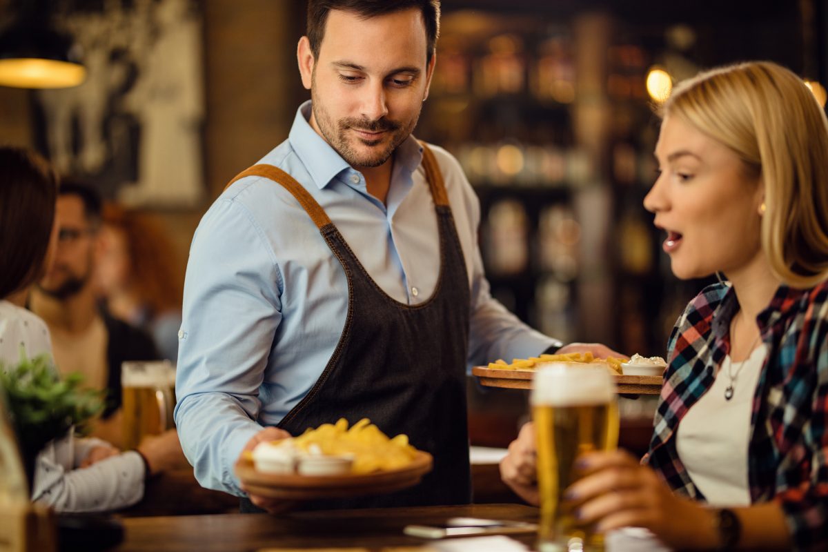 Waiter serving food to a table at a brewpub.