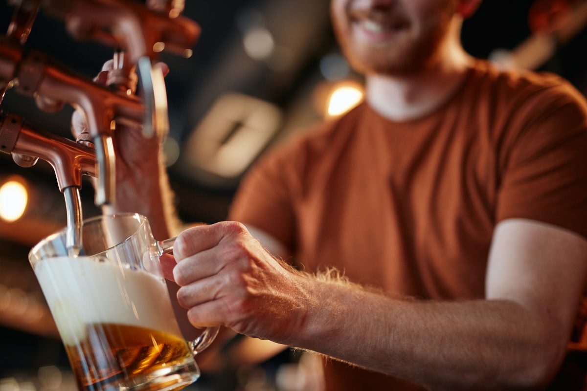 Close-up of bartender pouring beer from a tap.
