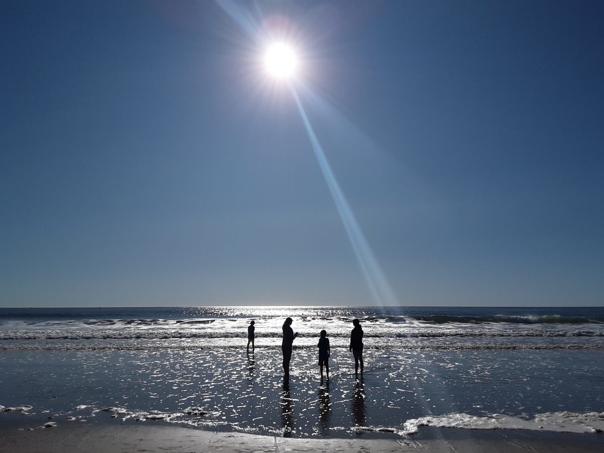 silhouette of a family of four playing in the waters of hampton beach, new hampshire.