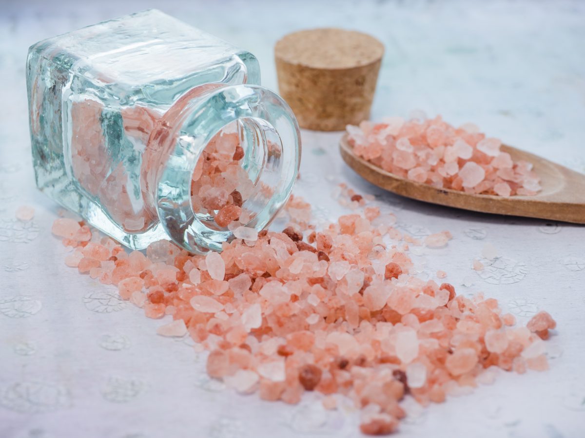 red sea salt in a jar next to a wooden spoon, one of the top hawaii souvenirs.