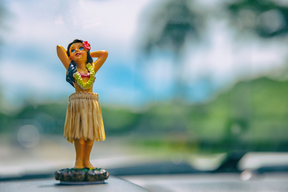 posing hula girl figurine on a car dashboard, one of the best hawaii souvenirs