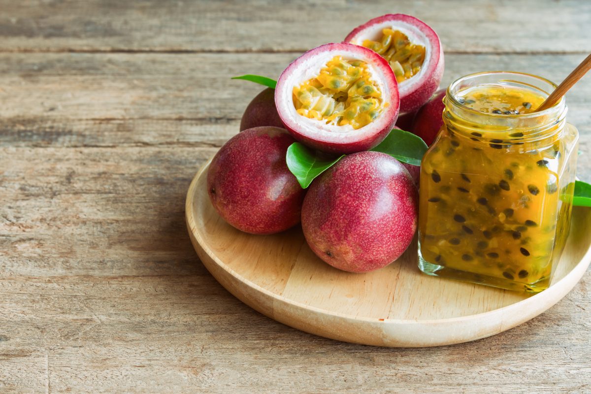 passion fruit jam in a glass container next to whole passion fruit.