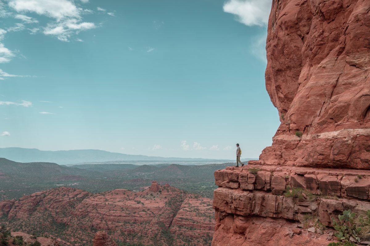 man standing atop cathedral rock, one of the believed sedona vortices. 