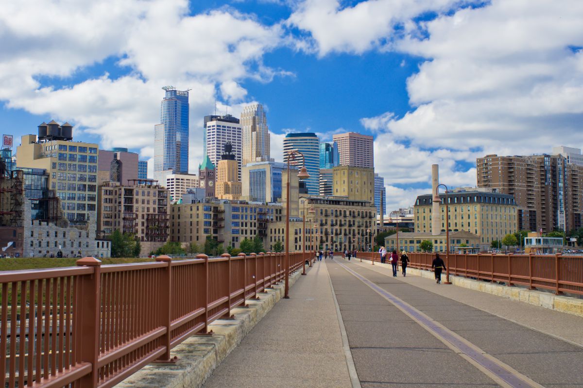 People walking over the Stone Arch Bridge, with the Minneapolis skyline in the background