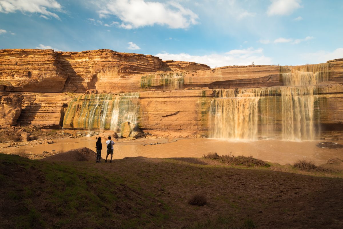 People standing at the base of Grand Falls in Arizona, one of the things to do in Flagstaff.