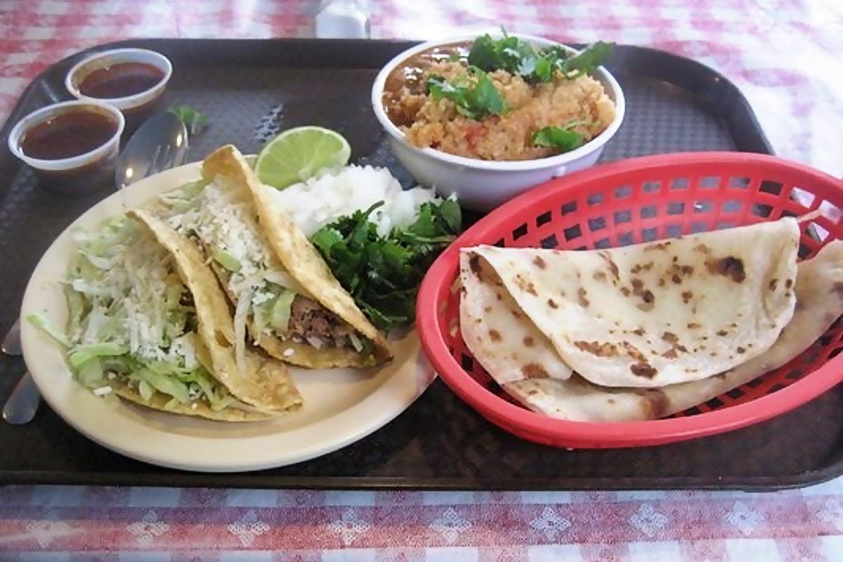 plate of pork tacos with a side of tortillas and rice and beans from las cuatro milpas.