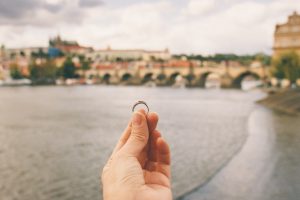 Woman holding an engagement ring front The Charles Bridge.