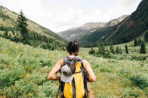 a beautiful back view shot of a women hiking in a beautiful meadow in the mountains
