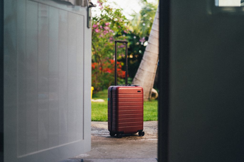 A brown carry on roll luggage outside in the yard A brown carry on roll luggage outside in the yard