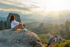 woman sitting on a cliff watching sunset