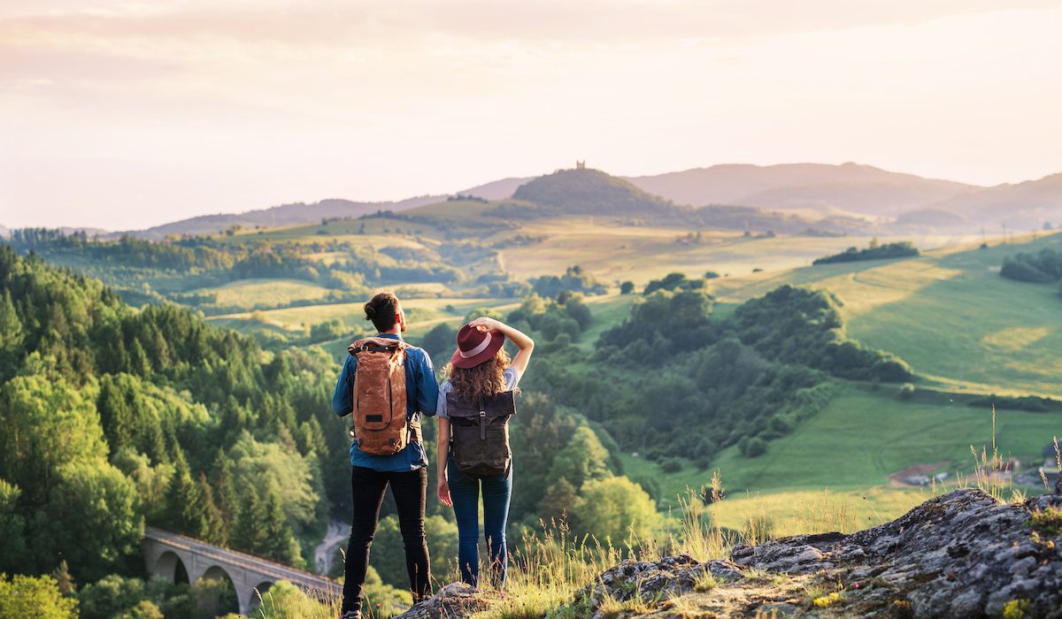 young tourist couple travellers with backpacks hiking in nature young tourist couple travellers with backpacks hiking in nature