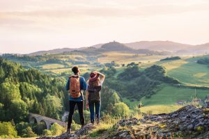 young tourist couple travellers with backpacks hiking in nature