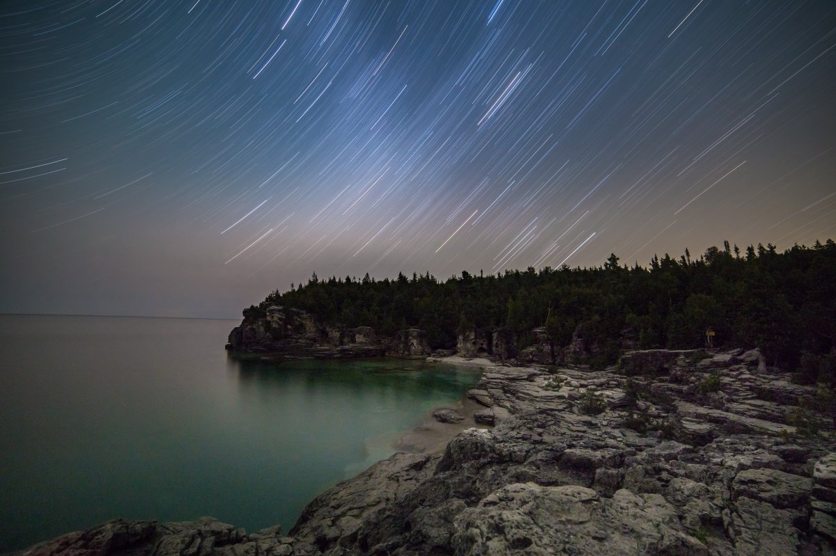 A time lapse photo of stars in the sky overlooking Bruce Peninsula National Park, Ontario, Canada