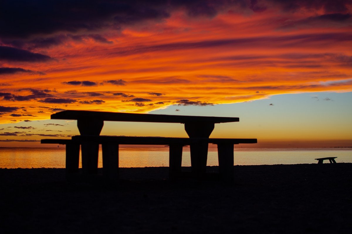 Picnic tables and benches stand along the shore at sunset in Point Pelee National Park, Ontario, Canada