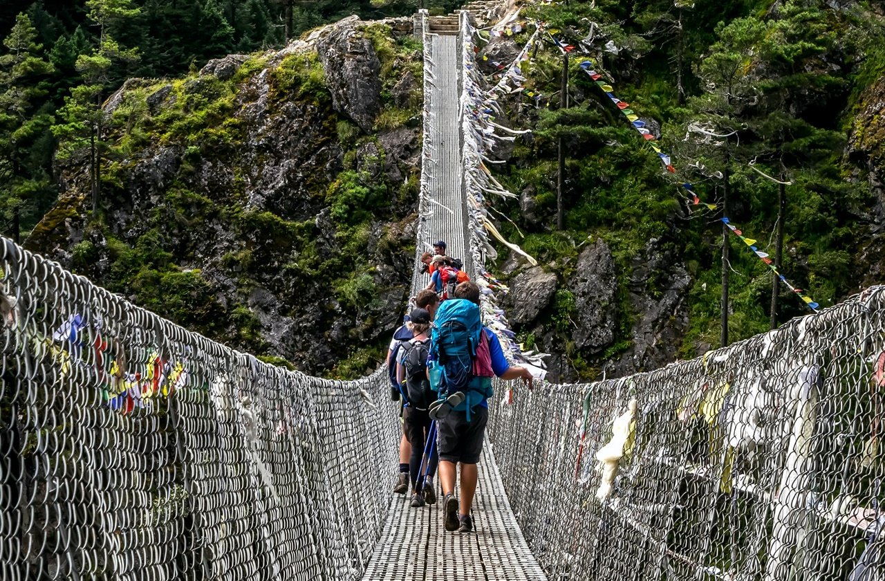 Nepal hiking Hikers crossing a rope bridge in Nepal