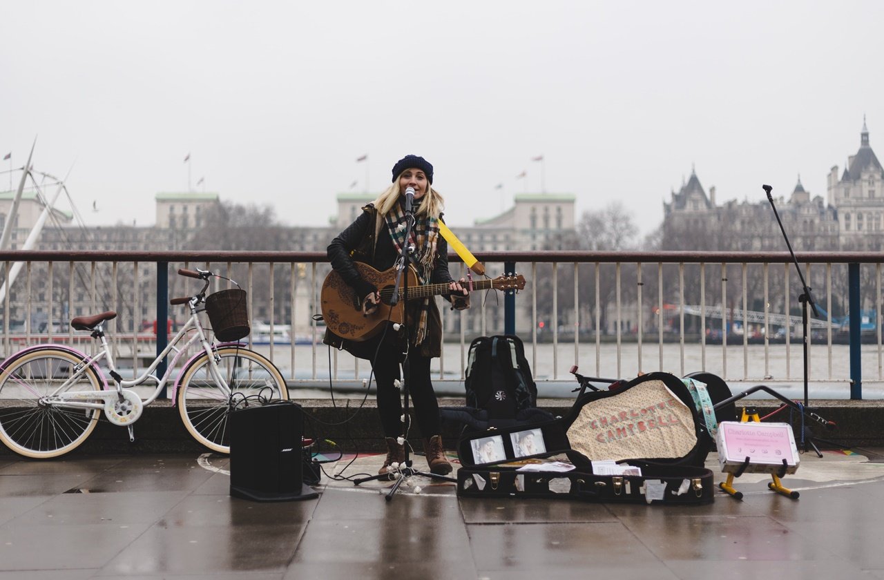 Busker Female singer playing the guitar on a street