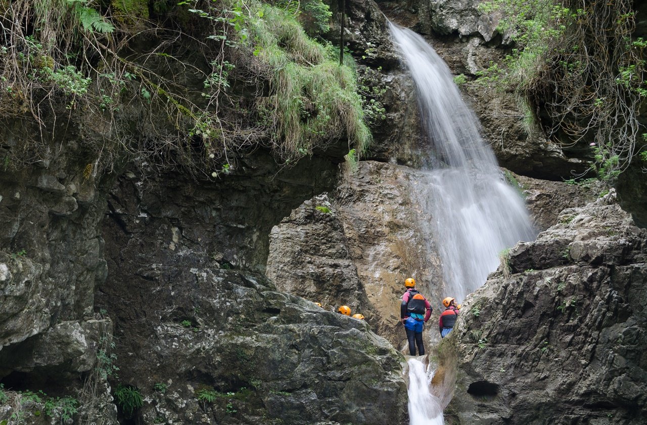 Canyoning Groups of canyoners near a waterfall